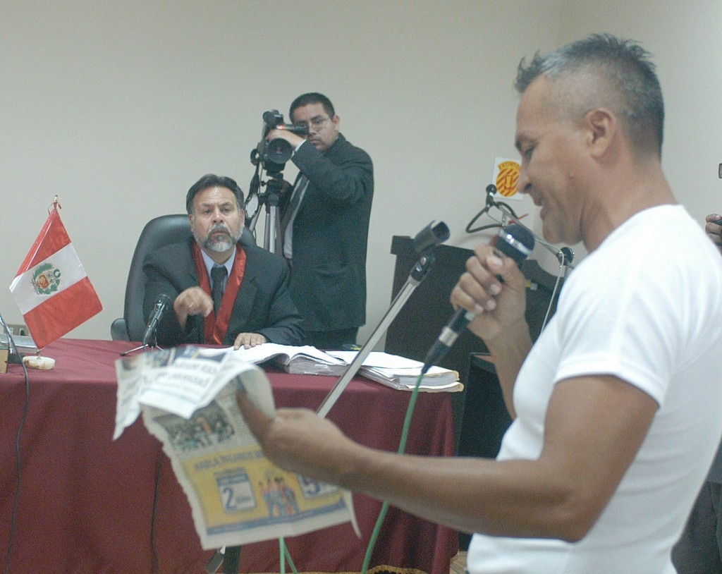 LIM02 - LIMA (PER'U), 12/01/04.- La sala Nacional de Terrorismo de Perú, aplazó para mañana, martes, la lectura de la sentencia, que estaba estaba prevista para hoy contra el narcotraficante Demetrio Chávez, alias "Vaticano" (dcha), acusado de colaborar con la banda maoísta Sendero Luminoso. En la imagen se ve a Demetrio Chávez mostrando un periódico donde supuestamente aparece un documento que lo exculpa de sus vínculos con el grupo. EFE/Sergio Urday